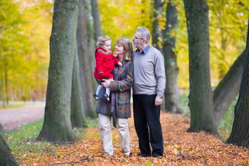 Fototapeta premium Happy family with a cute toddler girl walking together in a park