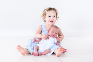 Laughing toddler girl playing with her newborn baby brother