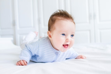 Happy laughing baby enjoying her tummy time in a white nursery