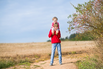 Happy brother and his baby sister playing together in a field