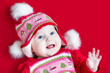 Happy laughing baby girl with blue eyes wearing a Christmas hat