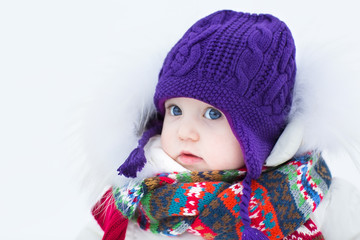 Cute baby girl wearing a warm winter hat and a colorful scarf