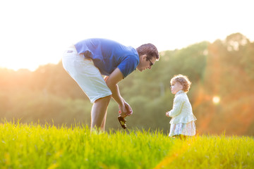 Father playing with his baby daughter in a field on a sunset