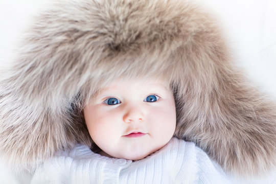 Funny curious baby girl in a huge winter hat