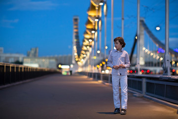 Little boy walking alone scared on a beautiful bridge in a dark