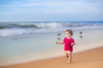 Fototapeta na wymiar Baby girl wearing a pink shirt and a diaper on a sea beach