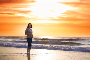 Fototapeta na wymiar Silhouette of a young pregnant woman with a sunset at a beach
