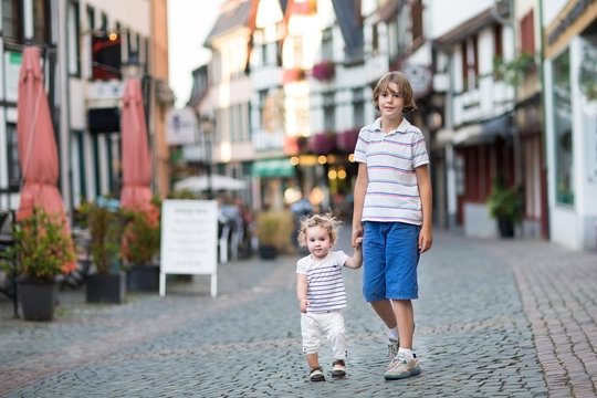 Brotehr and his little baby sister walking in a history town