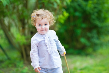 Cute curly baby girl playing in the garden