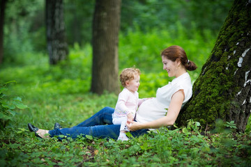 Young pregnant mother playing with her toddler daughter