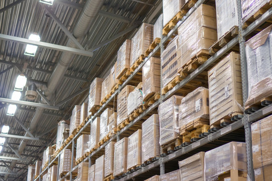 Rows of shelves with huge cardboard boxes in modern warehouse