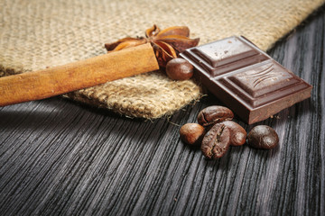 Chocolate bar and spices on wooden table