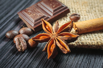 Chocolate bar and spices on wooden table