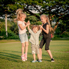 Fototapeta premium three happy little kids playing in the park in the day time