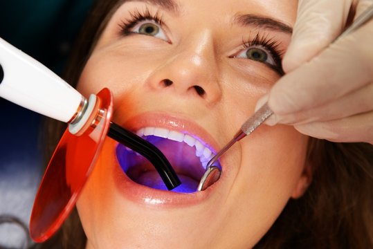 Young woman patient stopping treatment with dental UV light 