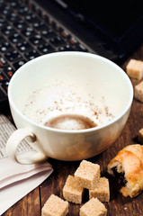 empty cup of coffee and a laptop on a wooden background