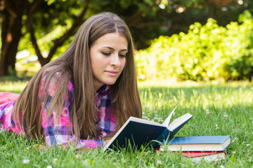 Fototapeta premium Beautiful young female reading a book, in the park