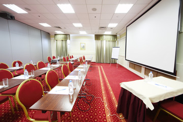 Tables with bottles, red chairs and projector in room
