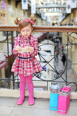 Little cute girl with pappers stands near wrought railings