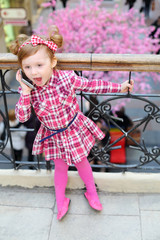 Little cute girl stands near wrought railings and shouts