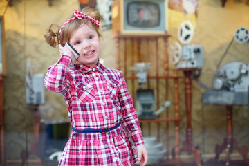 Little girl in pink talks by mobile phone and stands