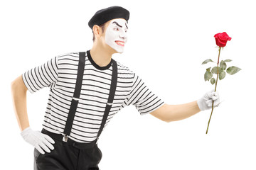 Male mime artist giving a rose flower