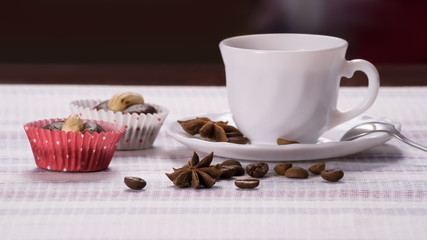 Cup of coffee decorated beans with cakes on a striped napkin