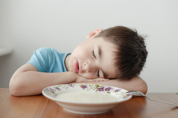 A tired boy sleeping over his porridge