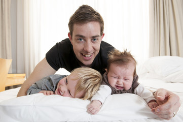 Fototapeta premium Young father playing with sweet baby girl and son
