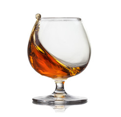 Splash of cognac in glass isolated on white background © artjazz