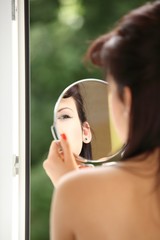 girl retro style applying make up looking at mirror indoor