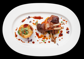 Grilled rack of lamb in oval plate isolated on black