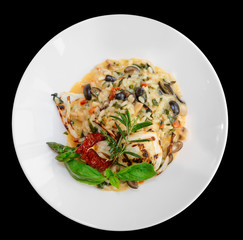 Risotto with tomatoes and herbs in plate, isolated on black