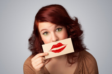 Happy pretty woman holding card with kiss lipstick mark