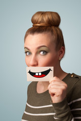 Happy pretty woman holding card with funny smiley