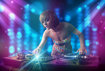 Dj girl mixing music in a club with blue and purple lights