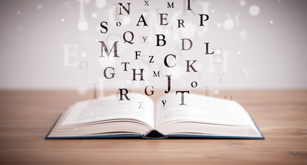 Opened book with flying letters