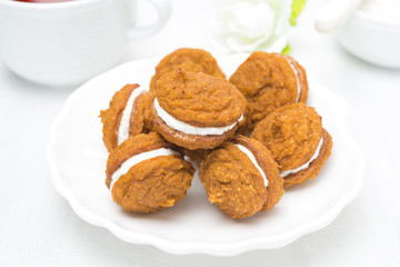 Pumpkin cookies with cream filling on a white plate