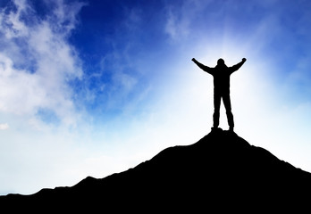 Silhouette of a winner on the mountain top.