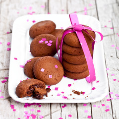 plate of fresh chocolate cookies with pink ribbon and confetti