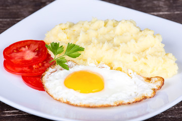 Mashed potatoes with fried eggs and tomato