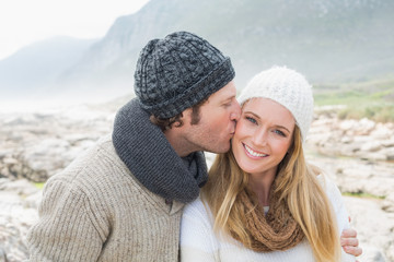 Man kissing a woman on rocky landscape