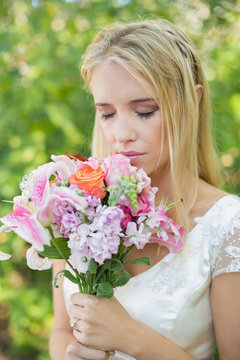 Blonde bride smelling her colourful bouquet
