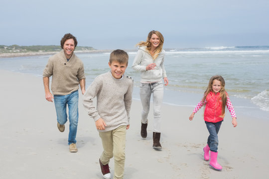 Happy family of four running at beach