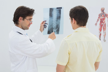 Obraz premium Male doctor explaining spine x-ray to patient