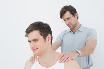 Male physiotherapist massaging a young mans shoulder