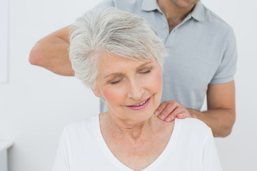 Male physiotherapist massaging a senior woman's neck