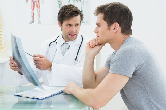 Male doctor explaining spine x-ray to patient - Powered by Adobe