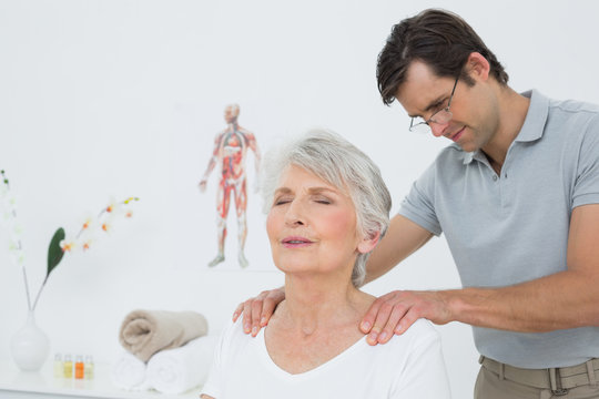 Male physiotherapist massaging a senior woman's shoulders