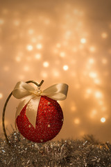 Dekoracja świąteczna - bombka ze wstążką na tle lampek